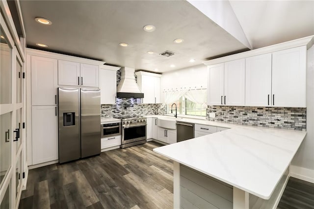 kitchen with kitchen peninsula, white cabinetry, premium range hood, and appliances with stainless steel finishes