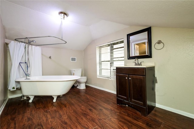 bathroom featuring a bath, vaulted ceiling, toilet, wood-type flooring, and vanity