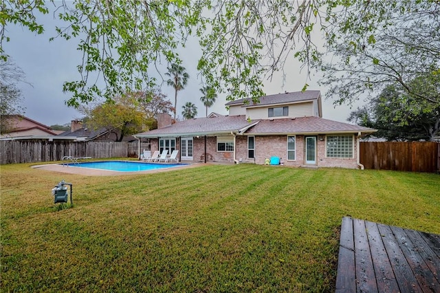 rear view of house with a lawn and a fenced in pool