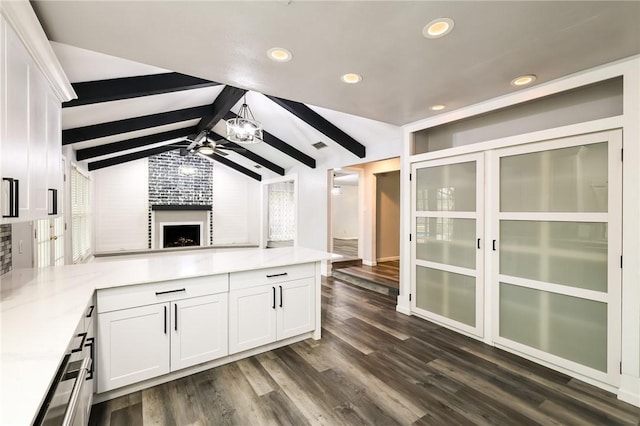 kitchen featuring a fireplace, dark wood-type flooring, lofted ceiling with beams, and white cabinetry