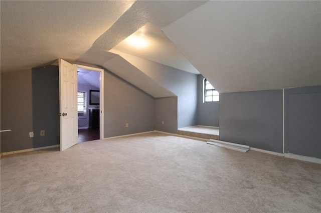 bonus room with lofted ceiling, a textured ceiling, and carpet