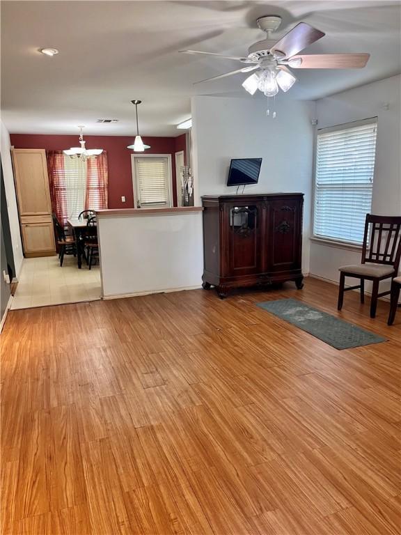 3101 Saskatchewan Dr, Corpus Christi, TX 78414 - unfurnished living room with light wood-style floors, plenty of natural light, a chandelier, and ceiling fan