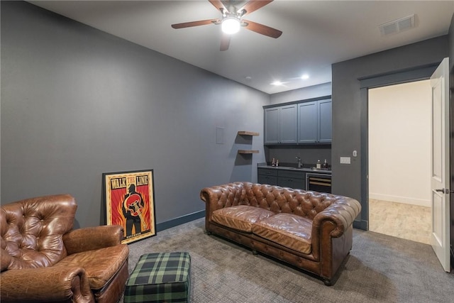 living room with visible vents, baseboards, beverage cooler, wet bar, and a ceiling fan