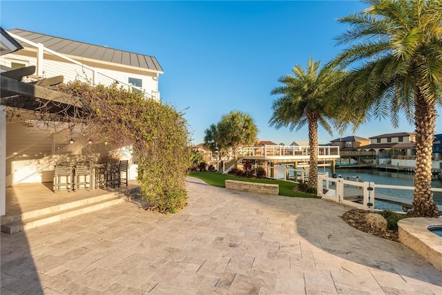 surrounding community with a patio area, a water view, outdoor dry bar, and a boat dock