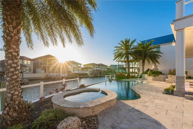 view of pool featuring a patio, a water view, and a pool with connected hot tub