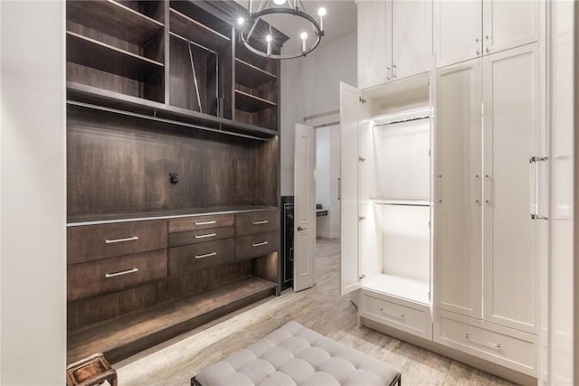 walk in closet with an inviting chandelier and light wood-style floors