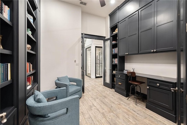 office space with visible vents, light wood-style floors, a ceiling fan, and built in study area