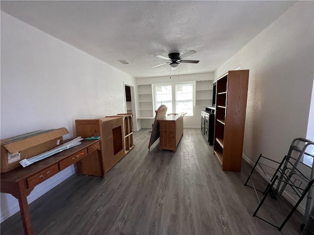 office area featuring built in features, a ceiling fan, baseboards, dark wood finished floors, and a textured ceiling