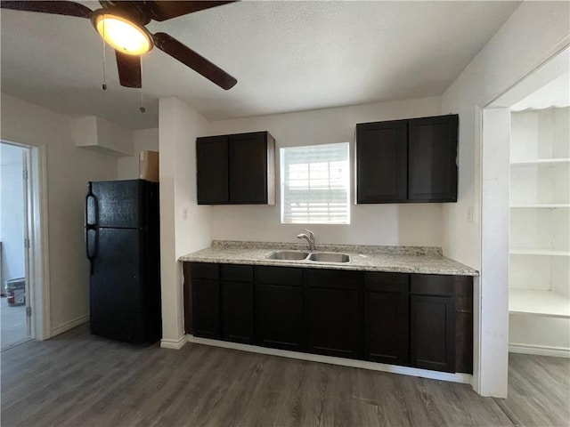 kitchen featuring a sink, freestanding refrigerator, light wood finished floors, ceiling fan, and light countertops