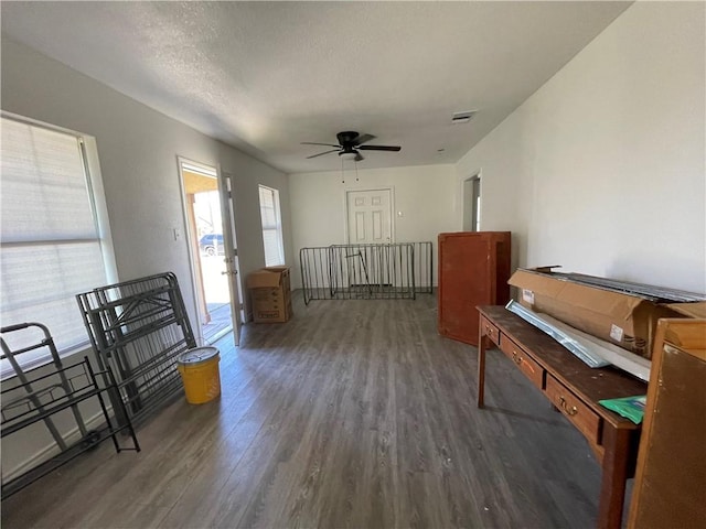 interior space featuring a ceiling fan, wood finished floors, visible vents, and a textured ceiling