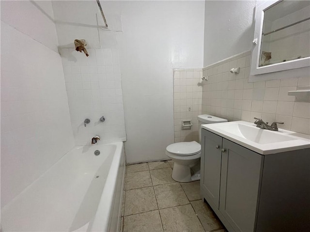 bathroom with tile patterned floors, toilet, tile walls, washtub / shower combination, and vanity