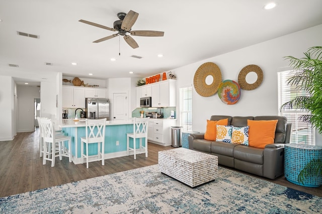 living room with dark hardwood / wood-style floors, ceiling fan, and sink