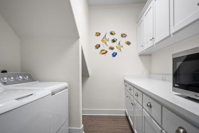 laundry room with washing machine and clothes dryer, cabinets, and dark hardwood / wood-style flooring