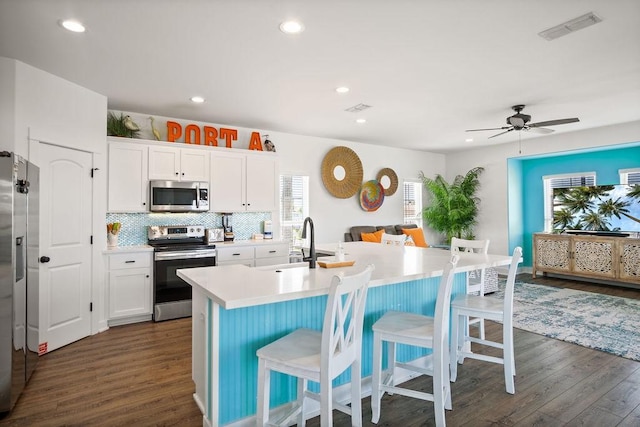 kitchen featuring stainless steel appliances, dark wood-style flooring, a sink, a breakfast bar area, and recessed lighting