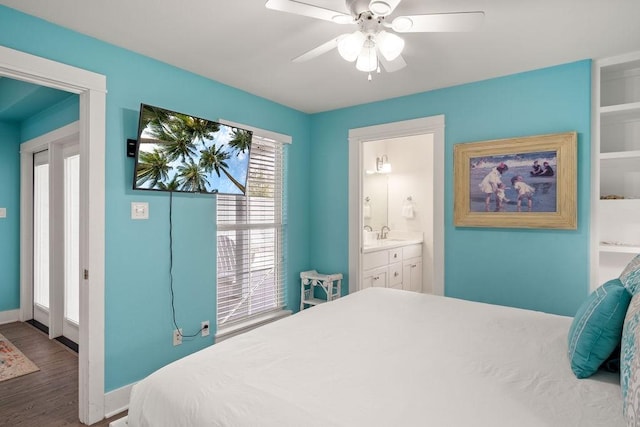 bedroom featuring wood finished floors, connected bathroom, baseboards, ceiling fan, and a sink