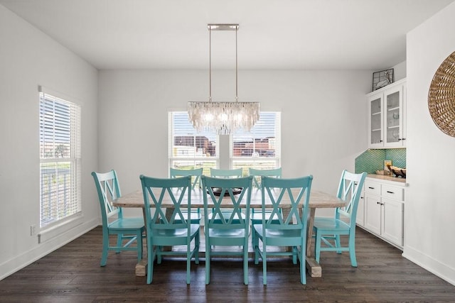 dining area featuring dark wood finished floors, a chandelier, and baseboards