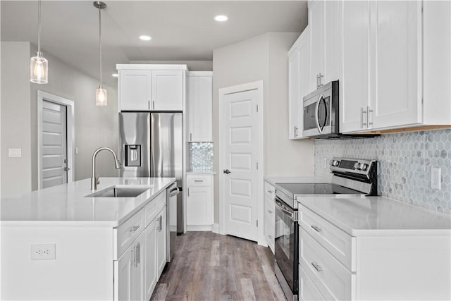15501 Cruiser St Unit A, Corpus Christi, TX 78418 - kitchen featuring stainless steel appliances, an island with sink, wood finished floors, decorative backsplash, and white cabinets