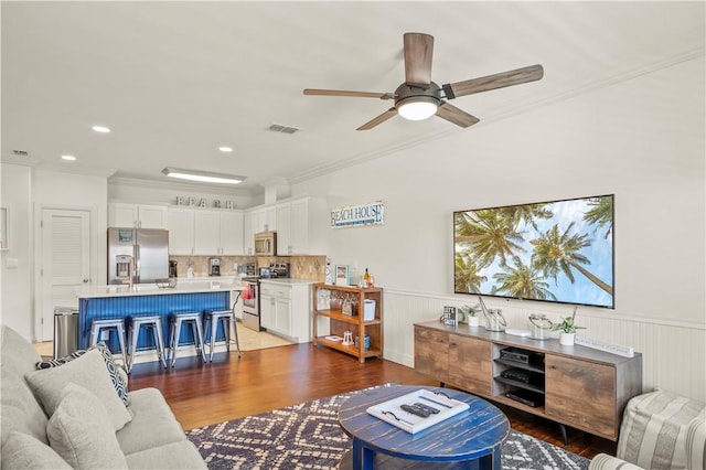 living room with crown molding, wood-type flooring, and ceiling fan