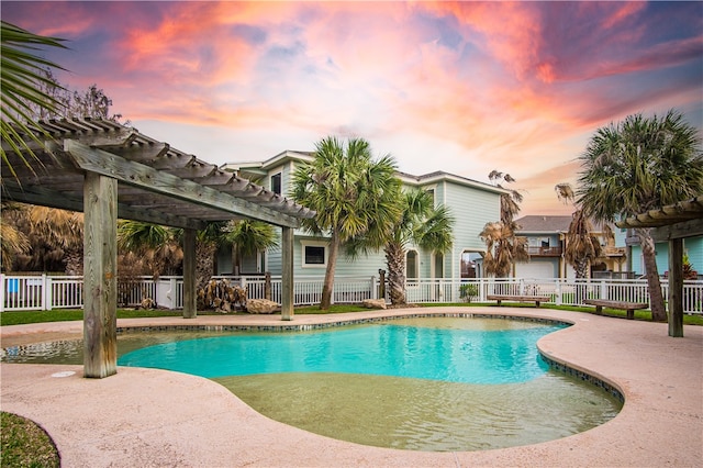 pool at dusk with a pergola and a patio area