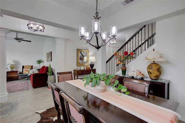 dining area with ornate columns, light wood-type flooring, ceiling fan with notable chandelier, and ornamental molding