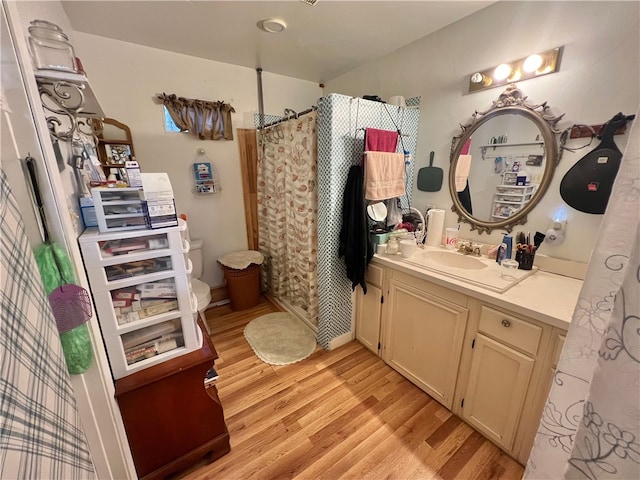 bathroom featuring hardwood / wood-style flooring, vanity, toilet, and curtained shower