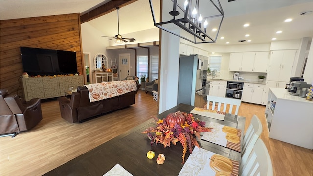 interior space with beam ceiling, high vaulted ceiling, ceiling fan with notable chandelier, and light wood-type flooring