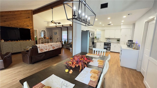 dining room featuring beam ceiling, high vaulted ceiling, ceiling fan with notable chandelier, and light wood-type flooring