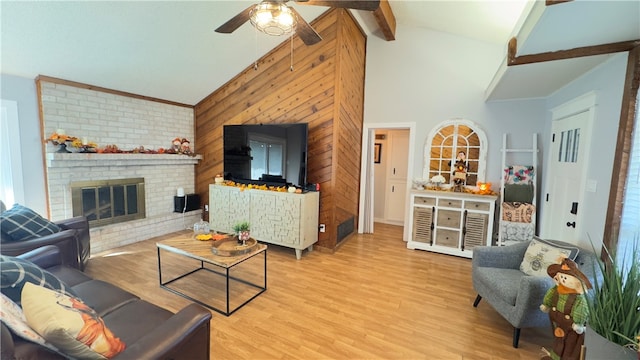 living room with a brick fireplace, ceiling fan, beam ceiling, high vaulted ceiling, and light hardwood / wood-style flooring