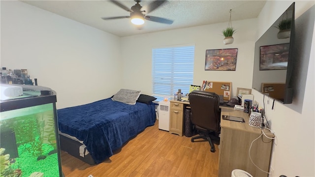 bedroom featuring a textured ceiling, light wood-type flooring, and ceiling fan