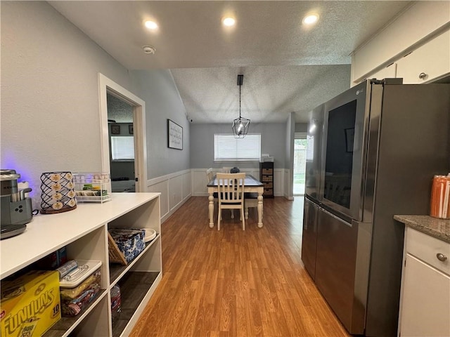 kitchen with stainless steel fridge, pendant lighting, light wood-type flooring, and white cabinets