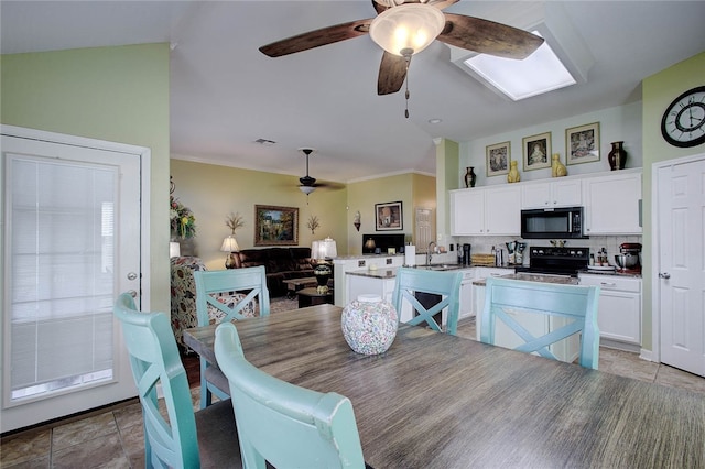 tiled dining space featuring ceiling fan, sink, lofted ceiling, and ornamental molding