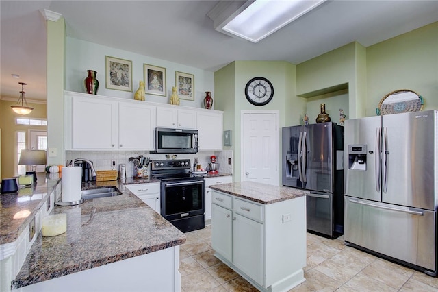 kitchen with stainless steel appliances, white cabinets, sink, a kitchen island, and stone countertops