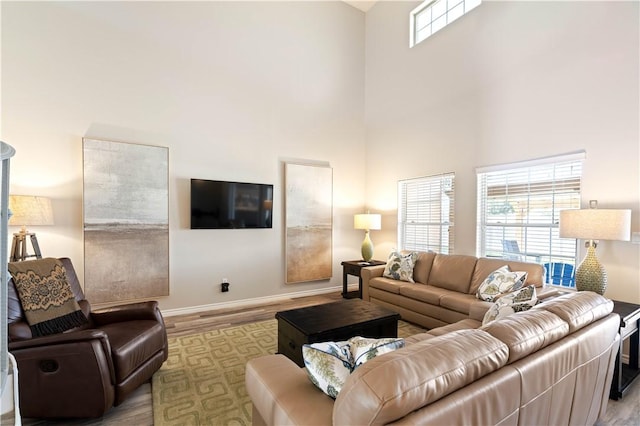 living room with a high ceiling, wood finished floors, baseboards, and a wealth of natural light