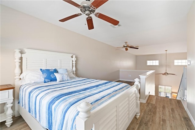 bedroom featuring visible vents, a ceiling fan, baseboards, and wood finished floors