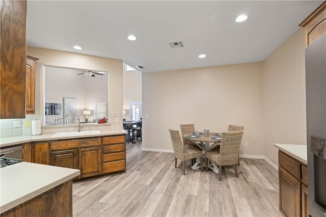 kitchen with light wood finished floors, visible vents, light countertops, decorative backsplash, and a sink