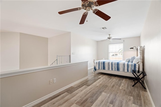 bedroom with visible vents, a ceiling fan, baseboards, and wood finished floors