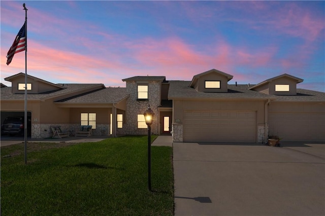 view of front of home featuring stone siding, roof with shingles, concrete driveway, a front yard, and a garage