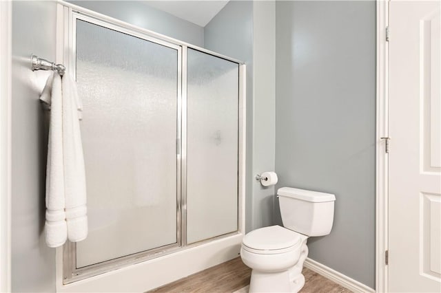 bathroom with an enclosed shower, toilet, baseboards, and wood finished floors