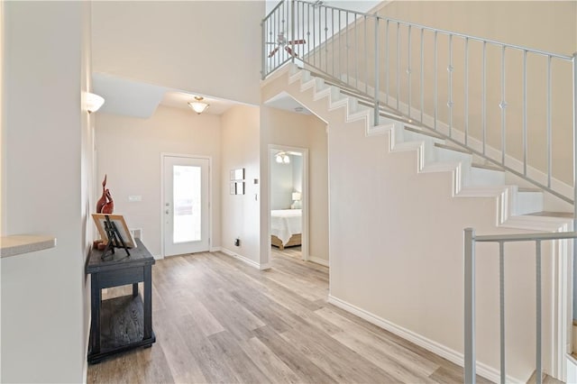 entrance foyer with baseboards, stairs, a high ceiling, and wood finished floors