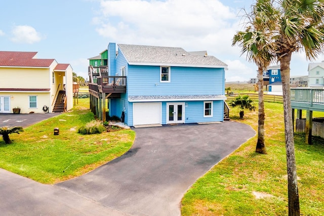 view of front of home with a garage, a front lawn, and a deck