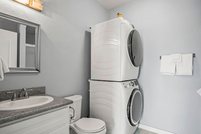 bathroom featuring vanity, stacked washer / dryer, and toilet