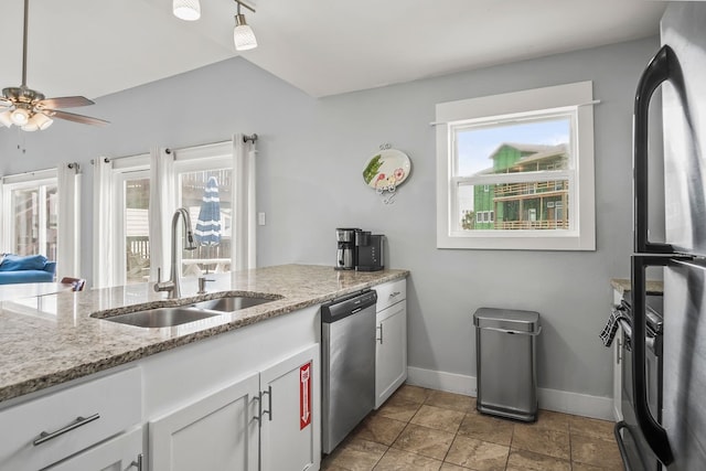 kitchen featuring stainless steel appliances, light stone counters, sink, ceiling fan, and white cabinetry