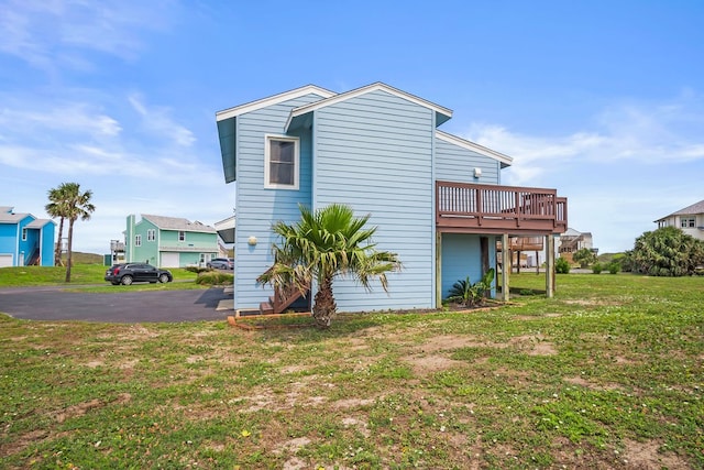 back of house with a deck and a lawn