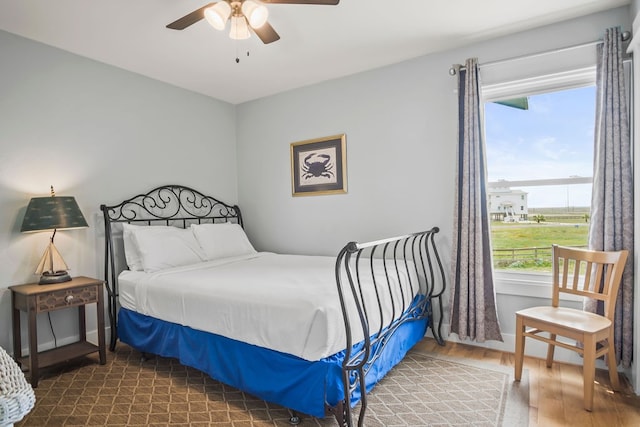 bedroom with multiple windows, wood-type flooring, and ceiling fan