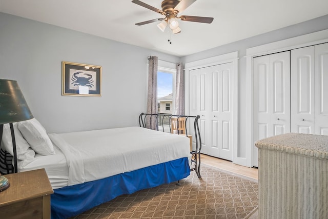 bedroom featuring hardwood / wood-style floors, two closets, and ceiling fan