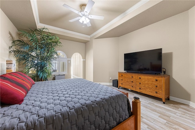 bedroom with ceiling fan, wood-type flooring, and a tray ceiling