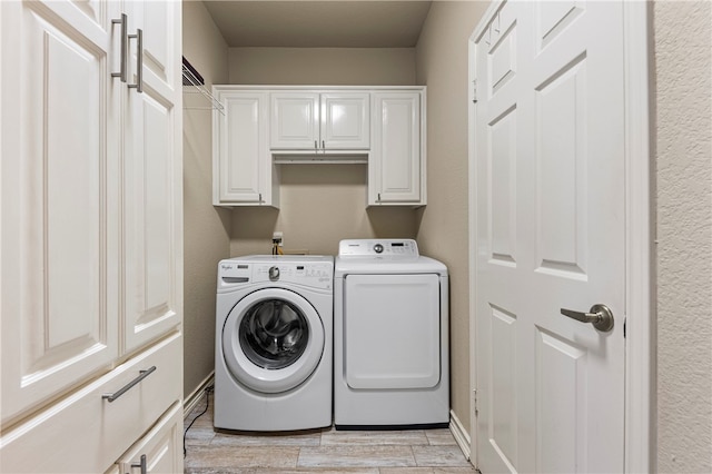 washroom featuring washer and dryer, cabinets, and light wood-type flooring