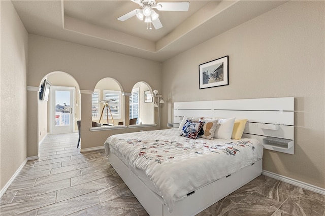 bedroom featuring a tray ceiling, ceiling fan, and light hardwood / wood-style floors