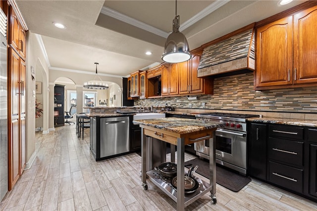 kitchen featuring pendant lighting, dark stone counters, crown molding, appliances with stainless steel finishes, and a kitchen bar