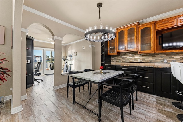 dining area featuring light wood-type flooring, ornamental molding, and decorative columns